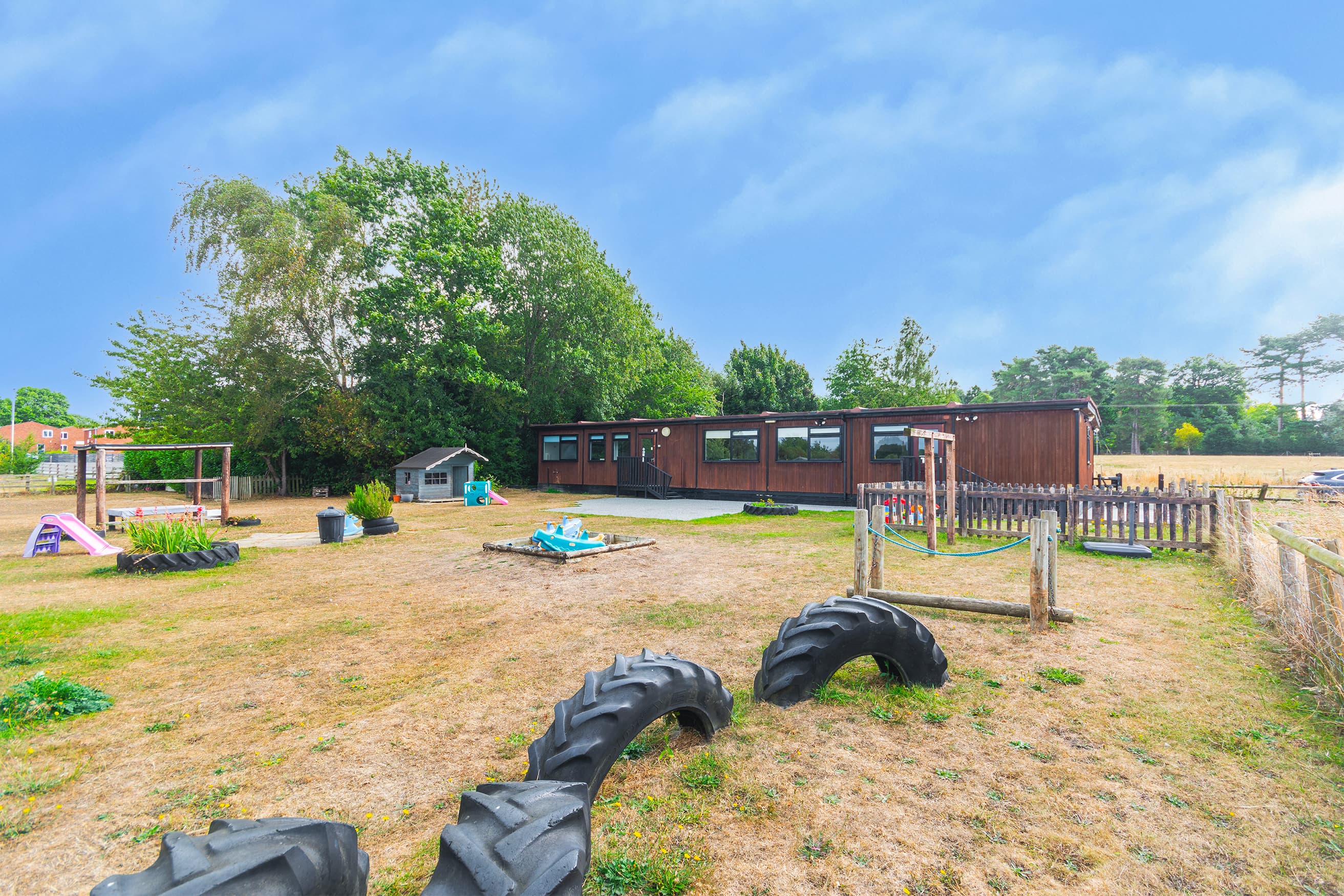 Bojangles Day Nursery outdoor play area with play equipment and gardens under a blue sky