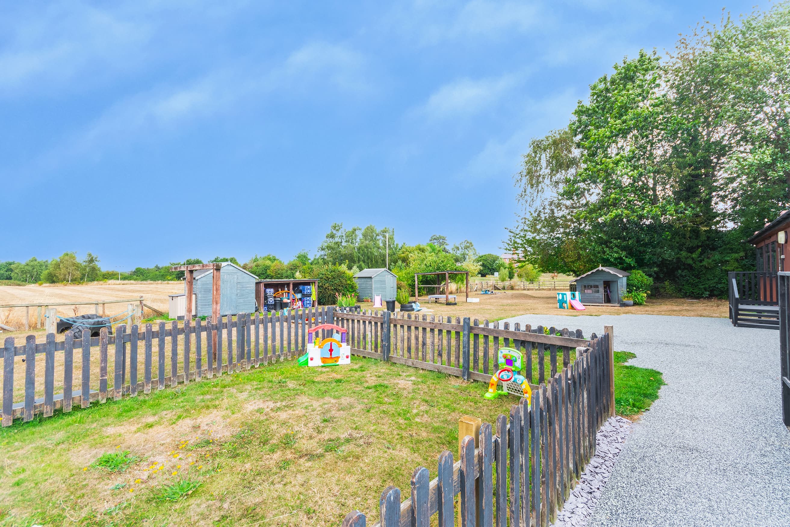 Fenced outdoor play area at Bojangles Day Nursery with colorful toys and Shropshire countryside views